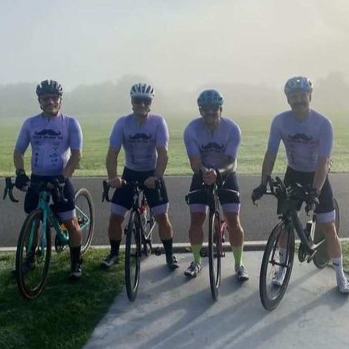 Photo of four cyclists wearing Movember-branded cycling shirts.