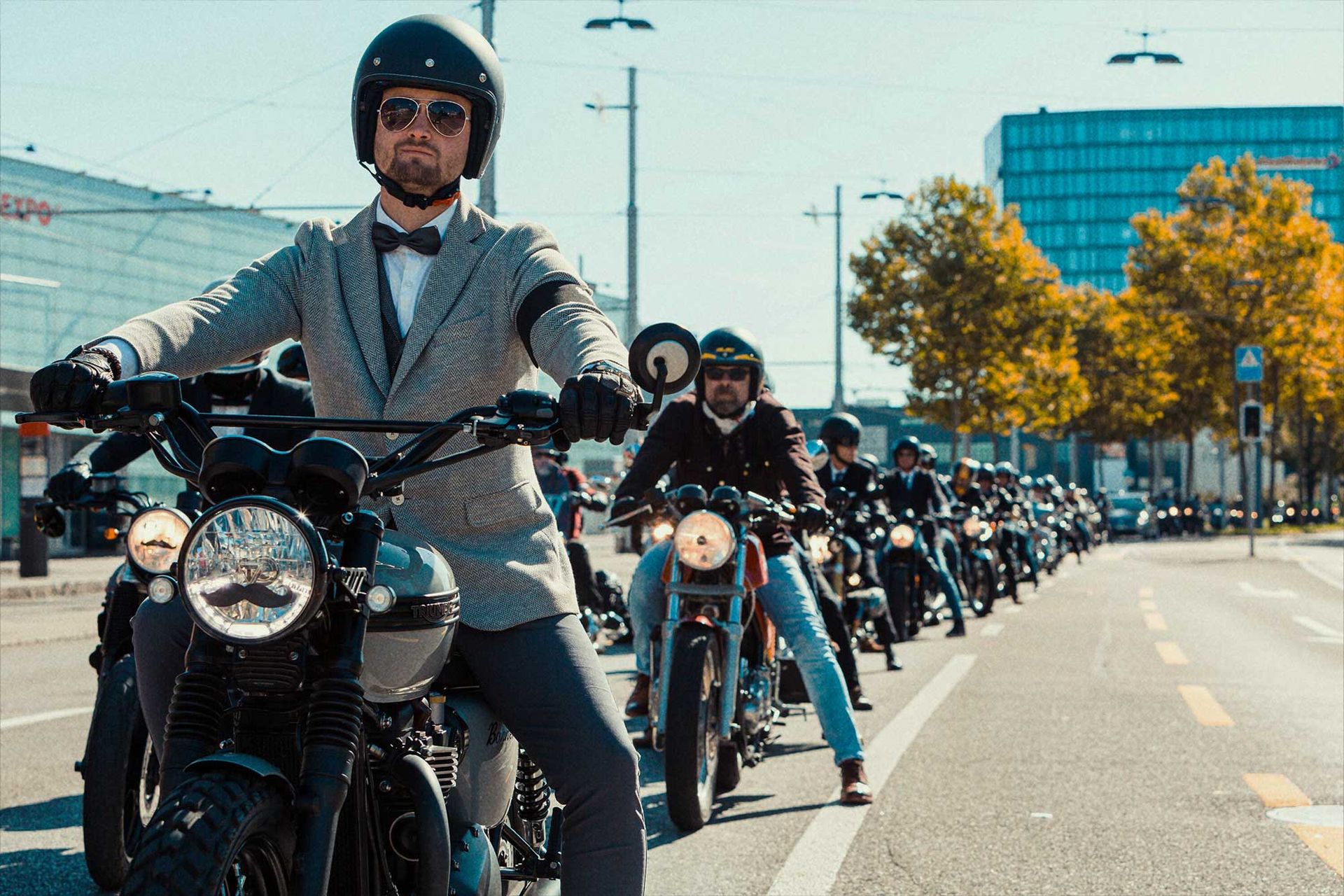 Photo of exceptionally well-dressed men riding classic motorcycles.