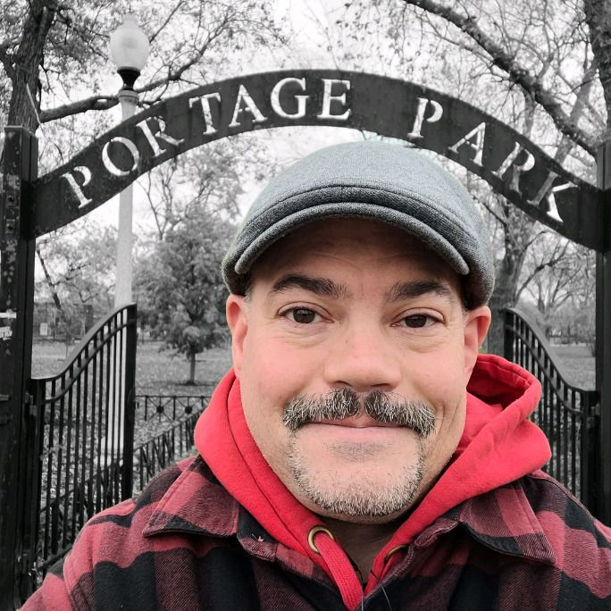 Photo of a man, looking to camera, sporting a fine moustache.