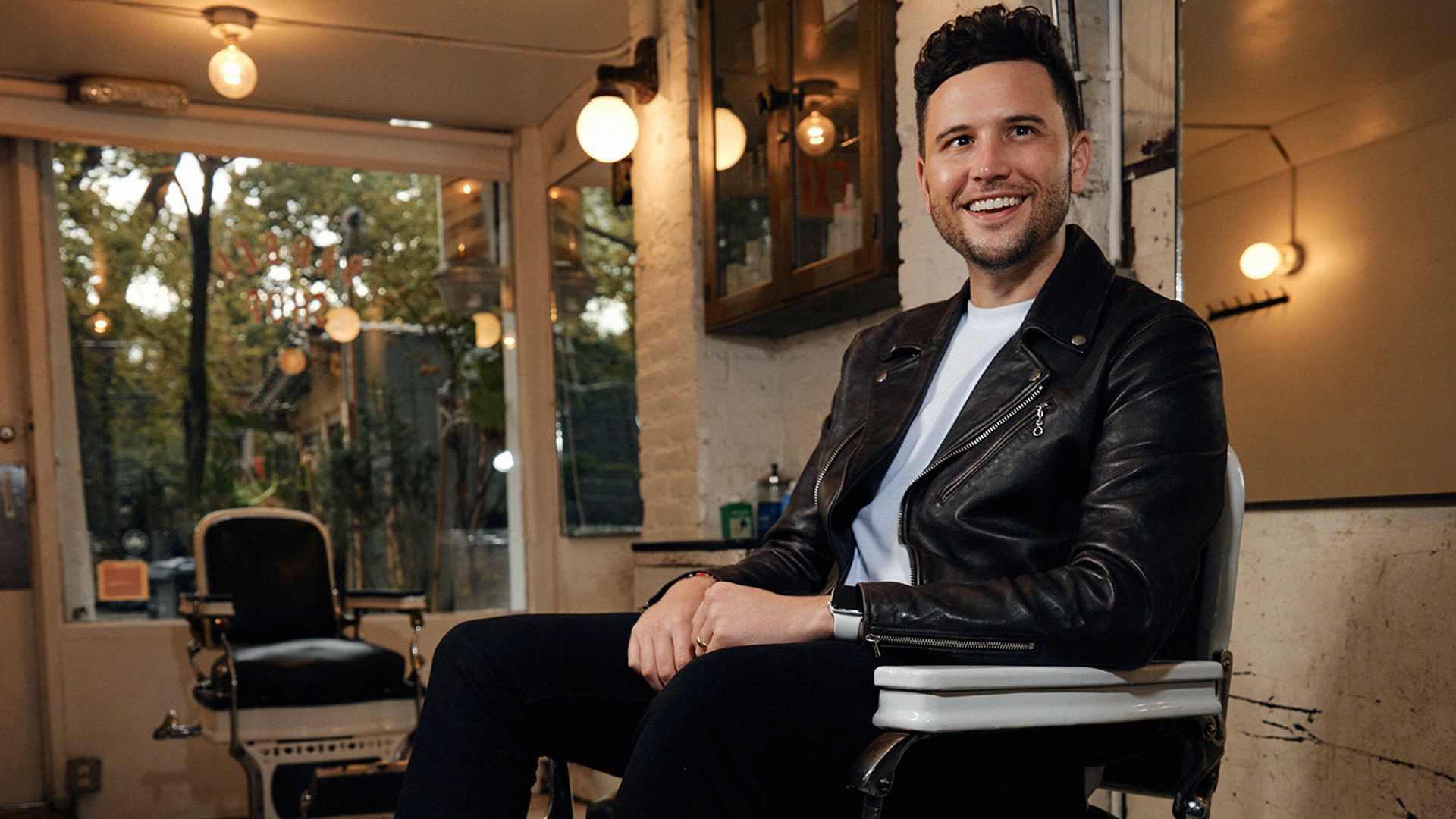 Man poses in the barber chair of a NYC barbershop