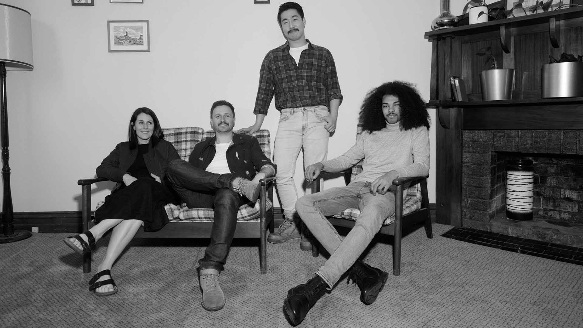 Black and white photo of relaxed group of friends sitting or standing and looking to camera.