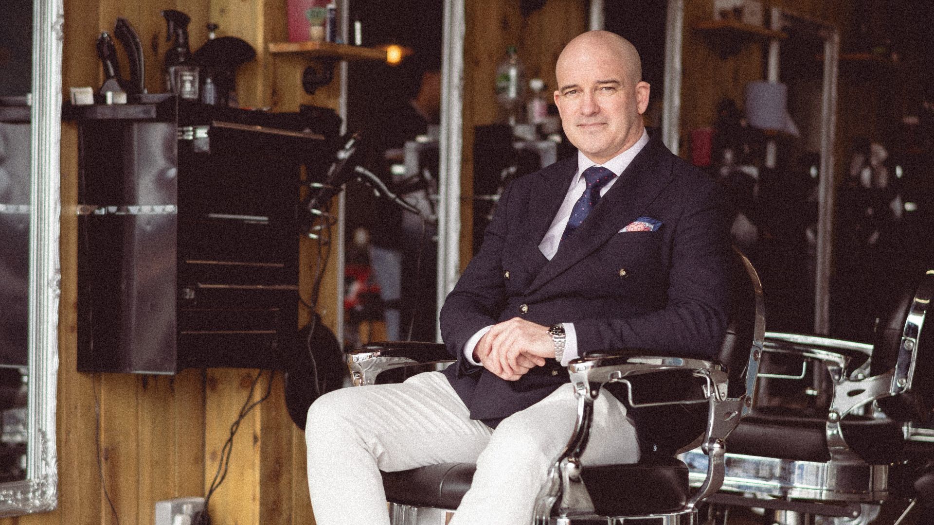 Sitting man in barber chair, looking to camera.