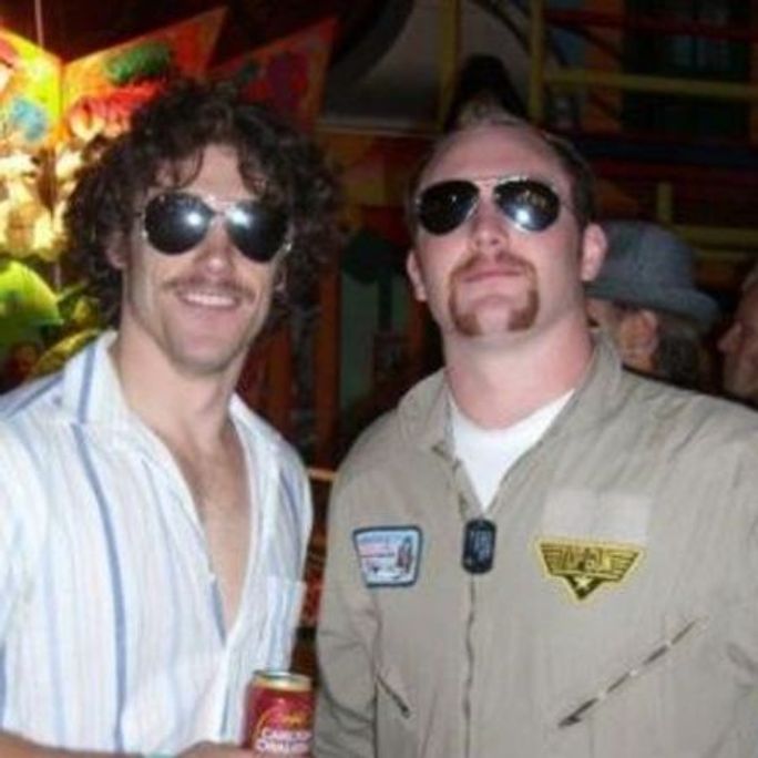 Photo of a two hip young men, wearing cool shades, smiling to camera.