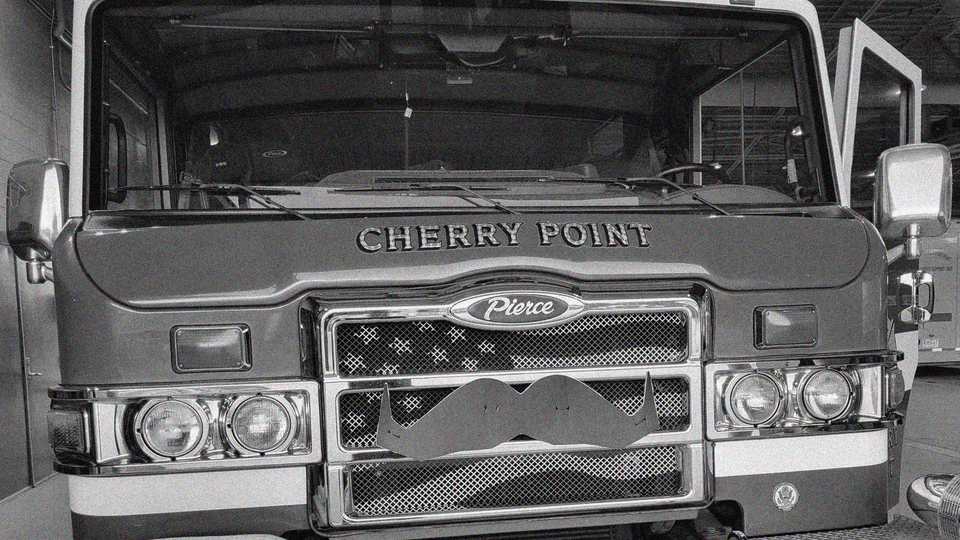 A black and white photo of the cropped front of fire truck. It says "Cherry Point" on it and has a moustache decal