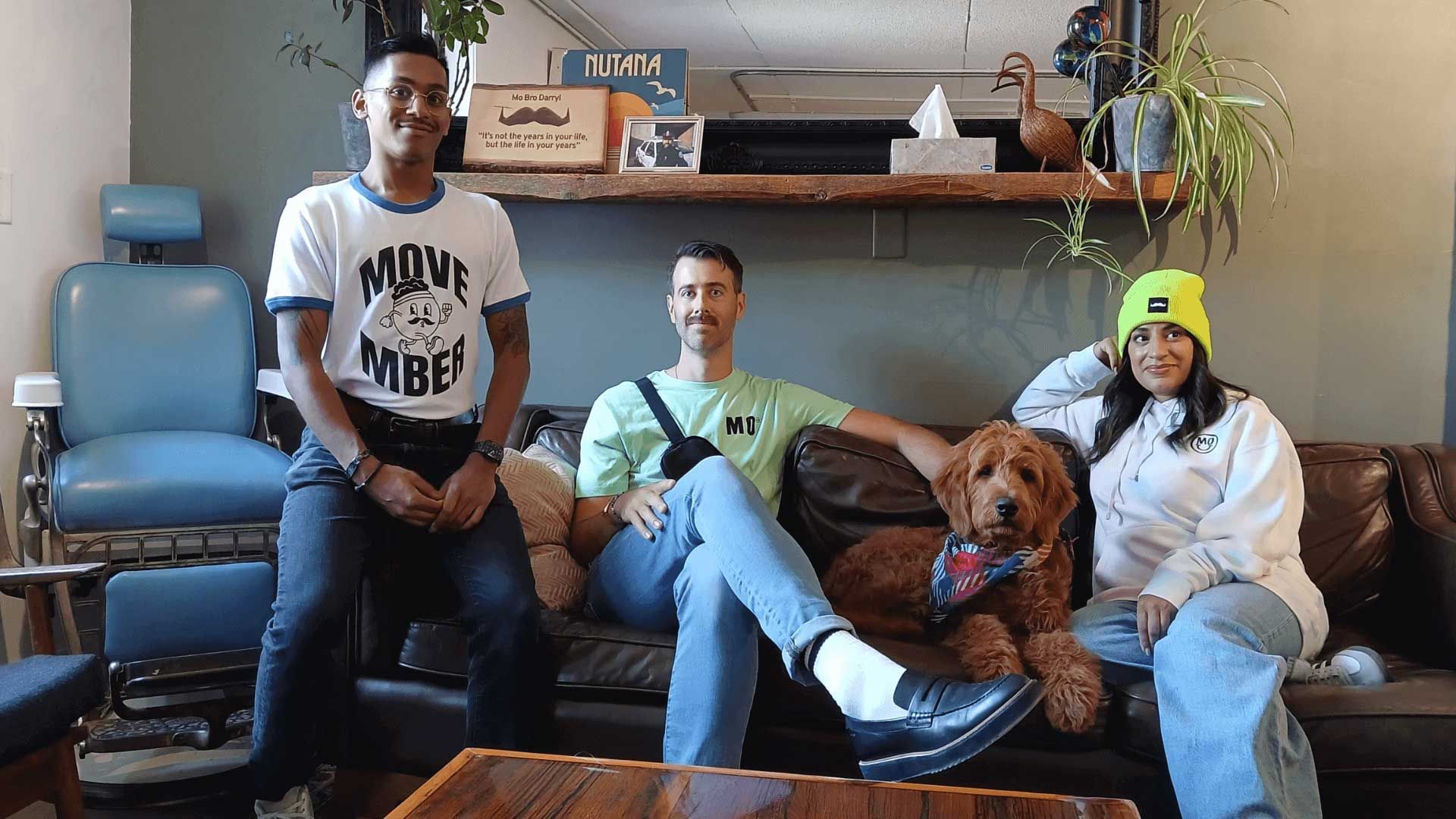 Photo showing three people and a dog, al smartly dressed (including the dog) in Movember-branded merchandise.