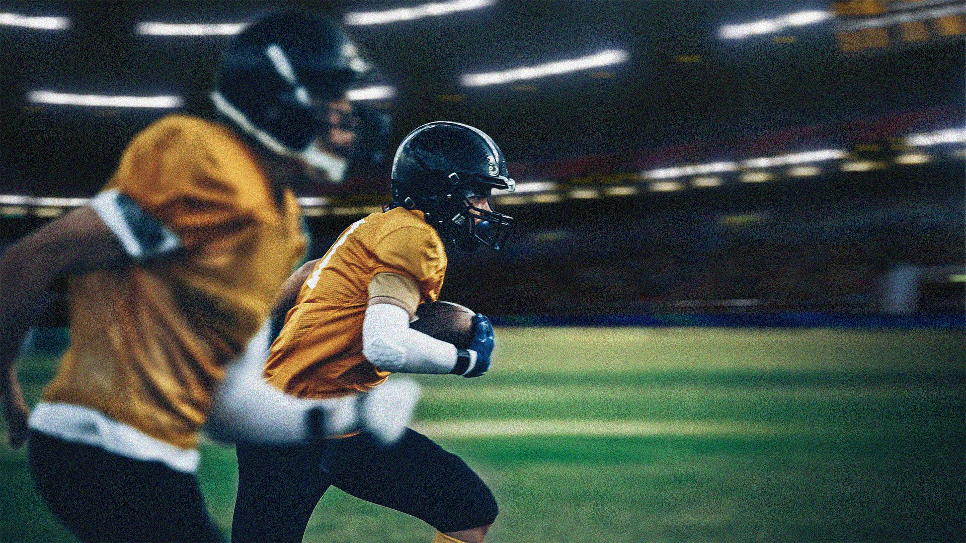 Two football players running on the field in close proximity