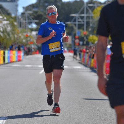 Athletic man in blue sports attire, running to camera as part of a marathon.