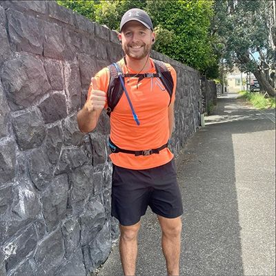 Smiling athletic man in orange sportswear giving a thumbs up to the camera.
