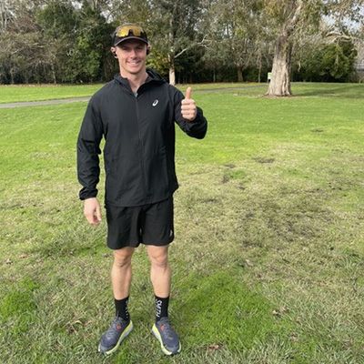 Smiling athletic man in black sportswear giving a thumbs up to the camera.
