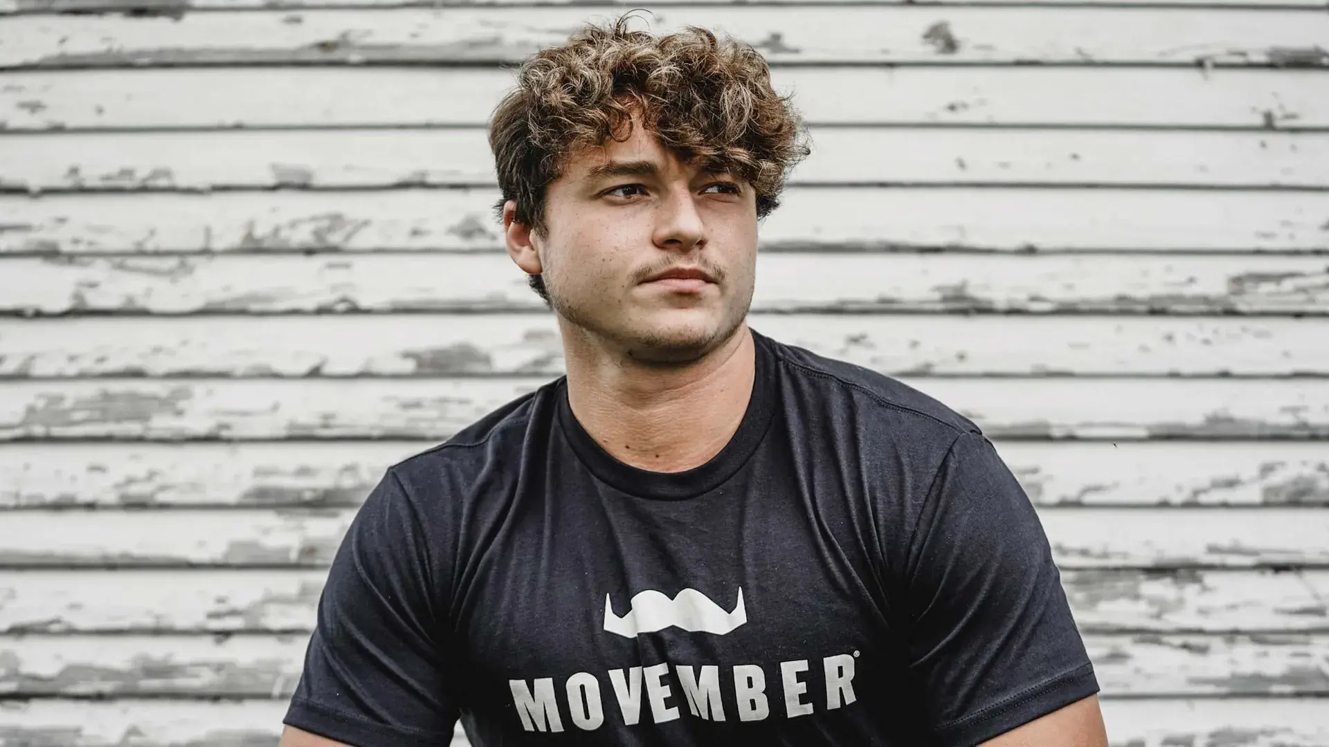 Young man sporting Movember-branded shirt.