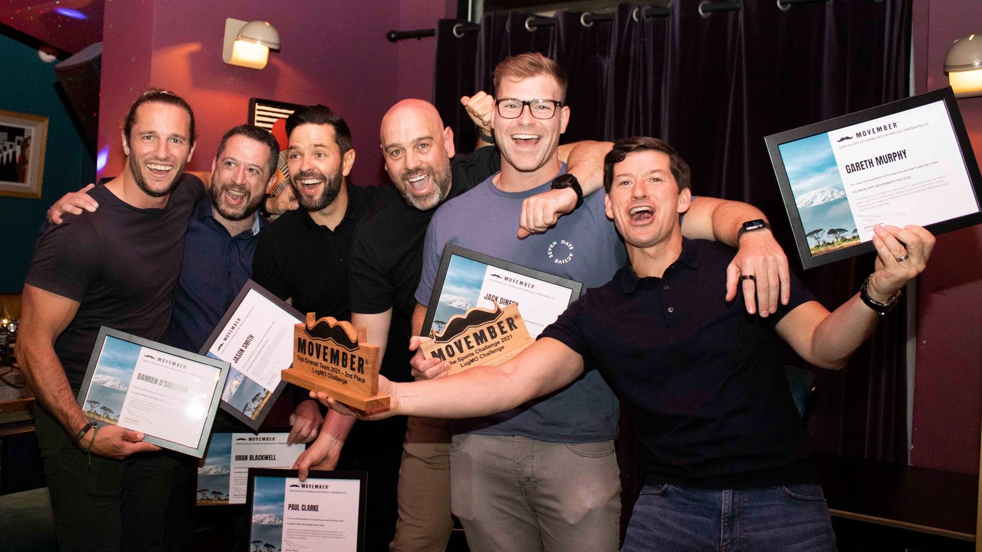 A photo of a group of Movember ambassadors with certificates and trophies.