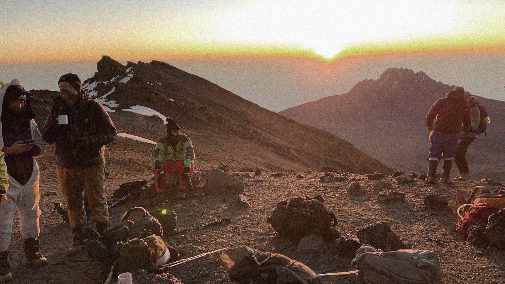 Hikers on Mount Kilimanjaro, wearing cold-weather gear and waking to a spectacular sunrise.