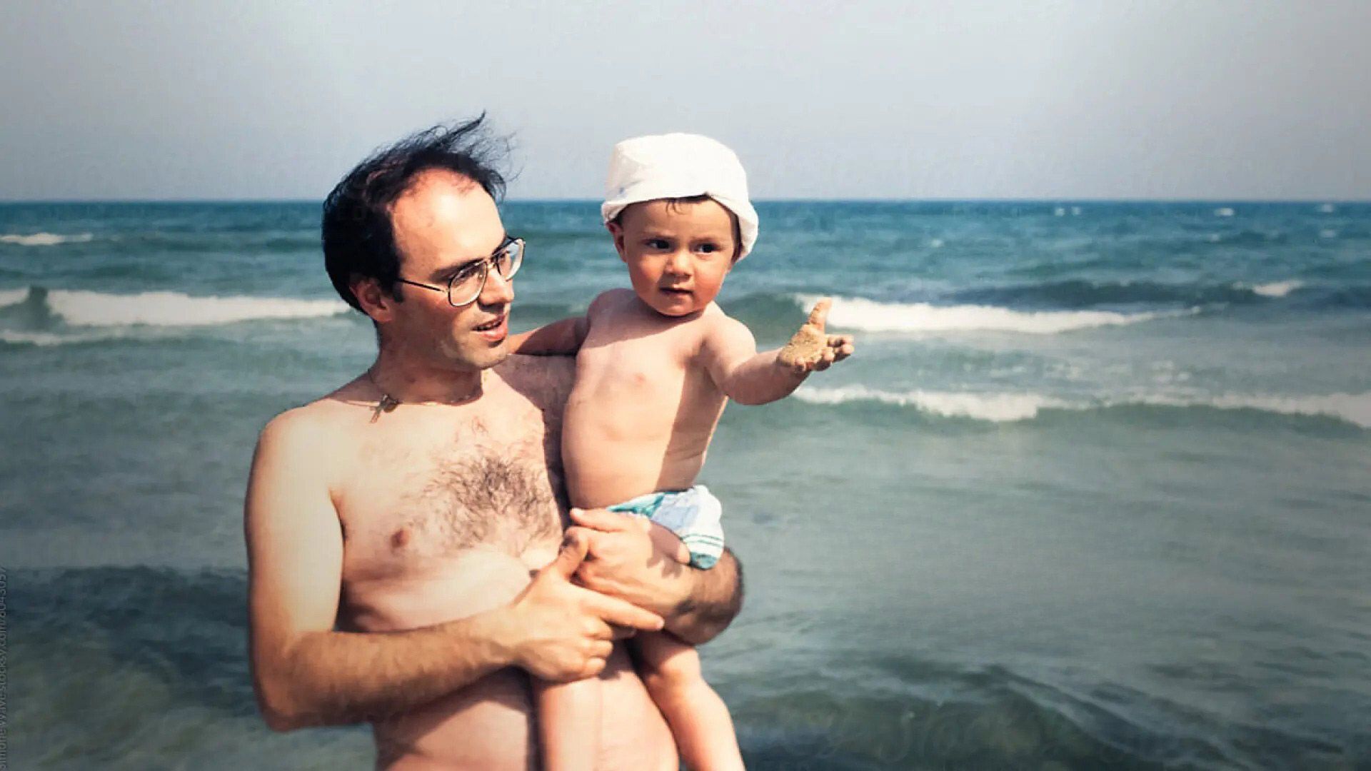 Photo of a father at a beach with an infant.
