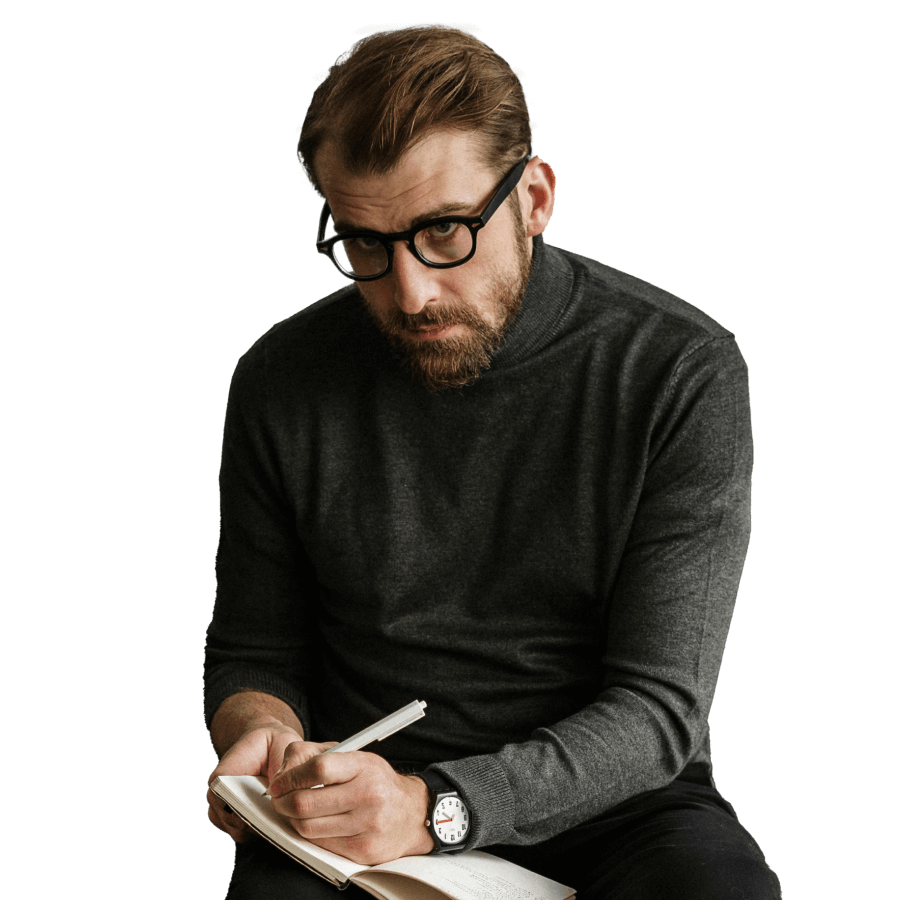 Photo of a man writing notes and looking to camera.