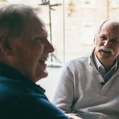 Photo of three senior men chatting casually at a table.
