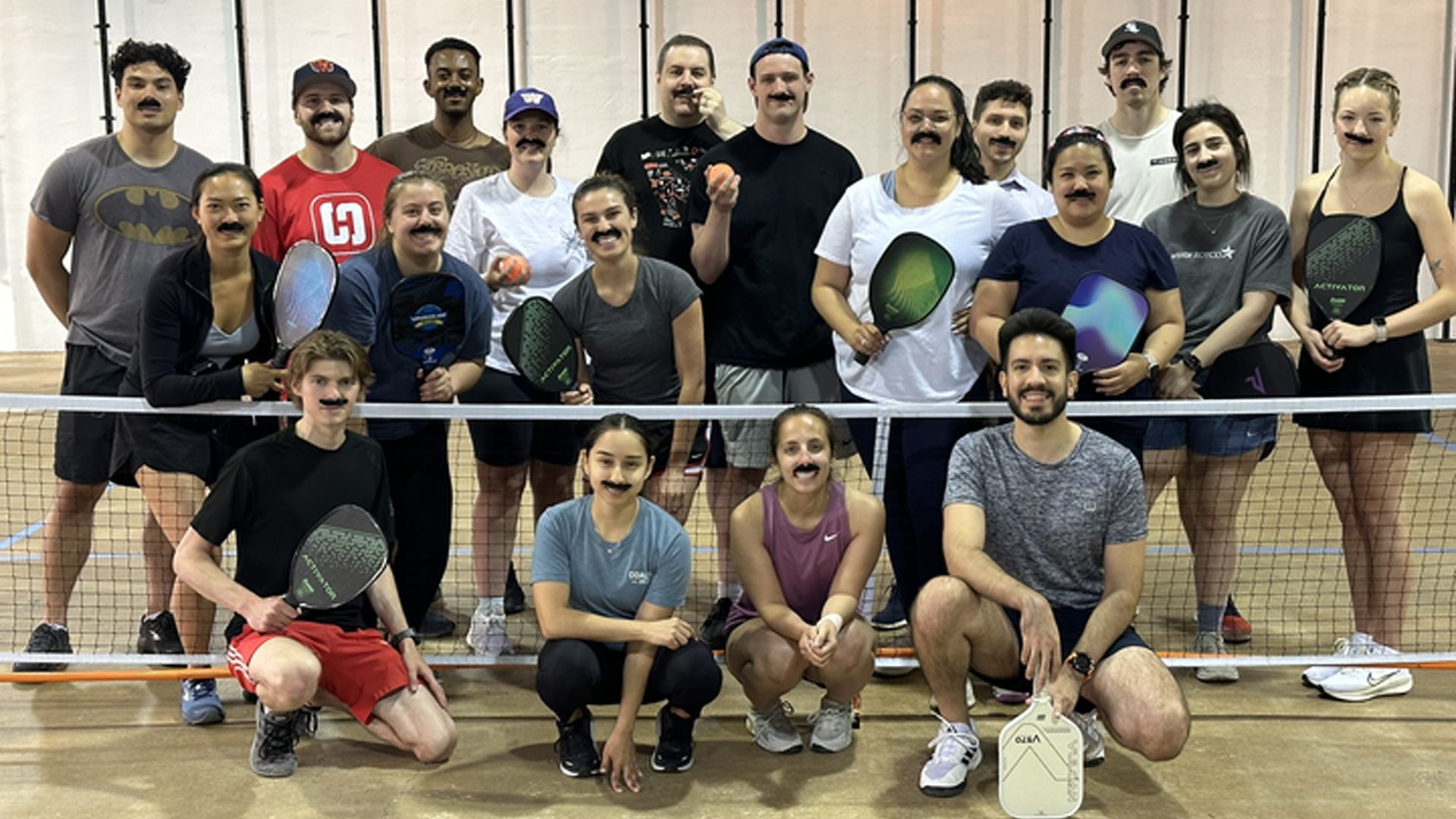 team poses on a pickleball court