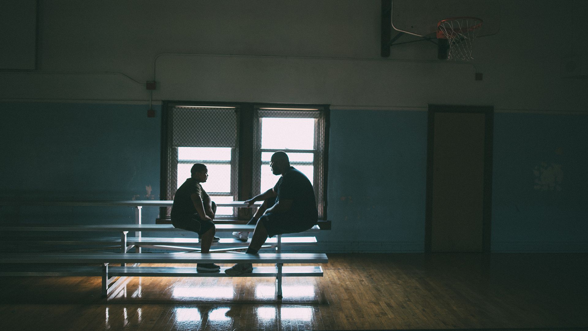 Mentor and youth in conversation in a basketball gym